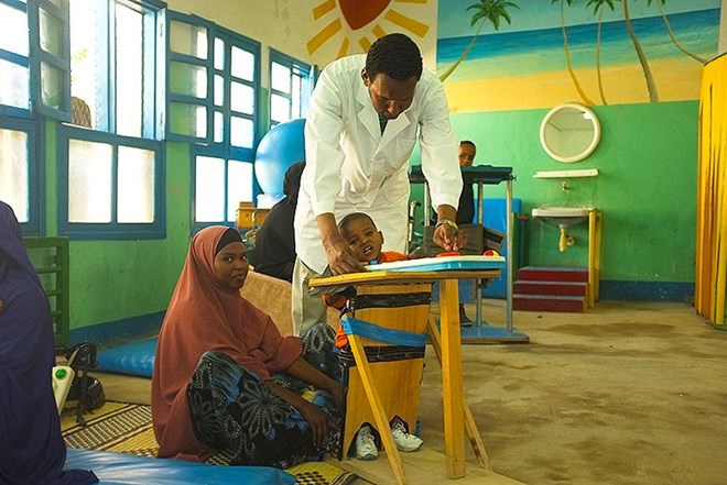 Abdillahi Mohammed, a doctor who has worked at DAN for 10 years, plays with one-year-old Abdifatah. Abdifatah's mother, 23-year-old Nimoali Ibrahim, traveled to Hargeisa from Berbera, a port city about two hours away, so her three children and young son could get therapy at DAN. (Photo: Amanda Sperber)