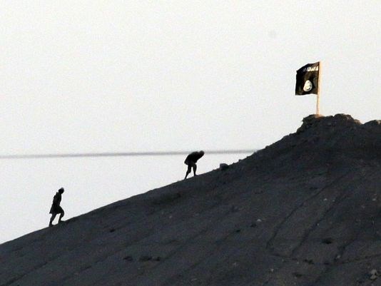 Militants with the Islamic State group are seen after placing their group's flag on a hilltop at the eastern side of the town of Kobani, Syria, in 2014.
(Photo: Lefteris Pitarakis, AP)