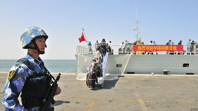 FILE - A navy soldier (L) of People's Liberation Army (PLA) stands guard as Chinese citizens board the naval ship "Linyi" at a port in Aden.