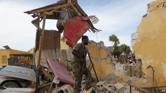 A Somali soldier stands amid ruins in Mogadishu, May, 9, 2016, after a suicide car bomber linked to al-Shabab struck traffic police headquarters. Somali and U.S. special forces led a joint raid Tuesday on a terrorist base.