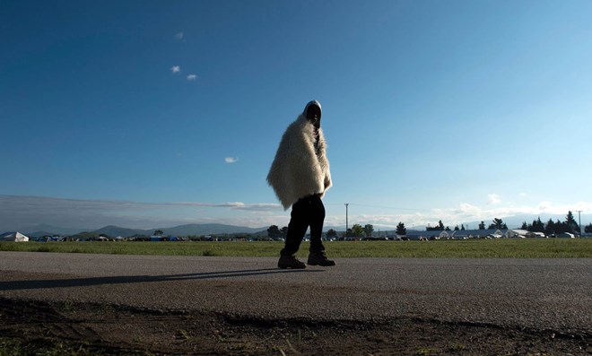 A man from Somalia wearing a blanket over his shoulders leaves a makeshift camp near the Greek-Macedonian border. Photographer: Tobias Schwarz/AFP via Getty Images