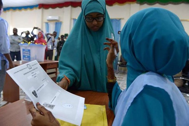 A Somali polling agent (right) explains the voting procedure to a voter before she casts her ballot in Baidoa, Somalia, on November 16, 2016. PHOTO | SIMON MAINA | AFP