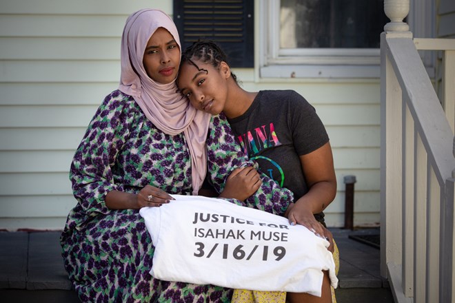 Asha Muse and her daughter Suban Hussein, 15, sit on the porch at their home in Portland on Friday with a memorial T-shirt for Muse's brother, Isahak Muse. In December, Mark Cardilli Jr. was convicted of manslaughter in Muse's shooting death and is expected to be sentenced this week. Credit: Troy R. Bennett / BDN