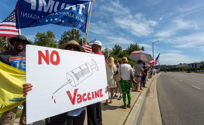 A protester held an anti-vaccination sign at a rally to reopen California as the coronavirus pandemic continued to worsen, on May 16, in Woodland Hills, California.Credit...David McNew/Getty Images