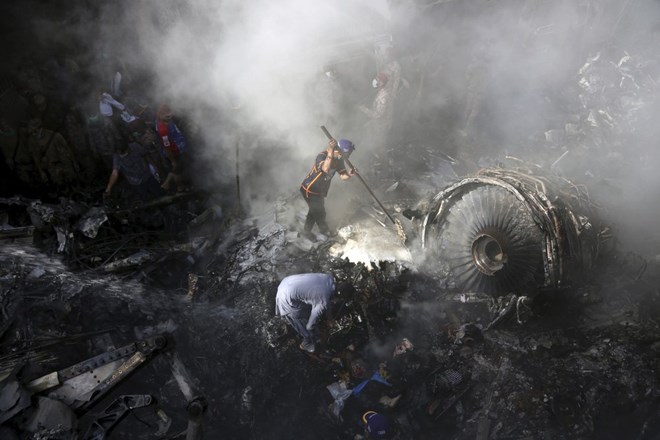 CORRECTS NUMBER OF PASSENGERS TO NEARLY 100, INSTEAD OF MORE THAN 100 - Volunteers look for survivors of a plane that crashed in a residential area of Karachi, Pakistan, May 22, 2020. An aviation official says a passenger plane belonging to state-run Pakistan International Airlines carrying nearly 100 passengers and crew crashed near Karachi's airport. (AP Photo/Fareed Khan)