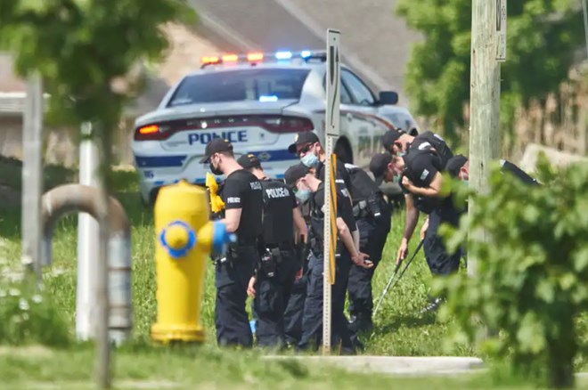 Police officers look for evidence at the scene of a car crash in London, Ontario, on Monday. Police say four people have died after several pedestrians were struck by a car Sunday. (Geoff Robins/The Canadian Press/AP)