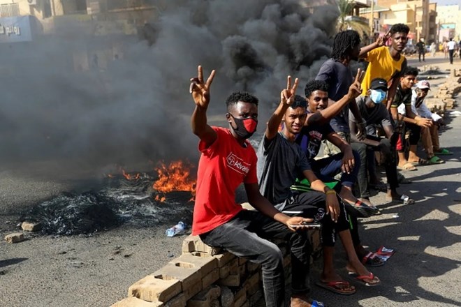 Sudanese protesters flash victory signs Monday as they burn tires to block a road in Khartoum to denounce the army's detention of members of Sudan's government. (AFP/Getty Images)