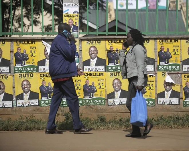 People walk in front of election posters in Eldoret, Kenya, Wednesday Aug. 10, 2022. Kenyans are waiting for results in the presidential elections that saw opposition leader Raila Odinga face Deputy President William Rutoto in their bid to succeed President Uhuru Kenyatta who stayed in power for a decade.  BRIAN INGANGA / AP PHOTO
