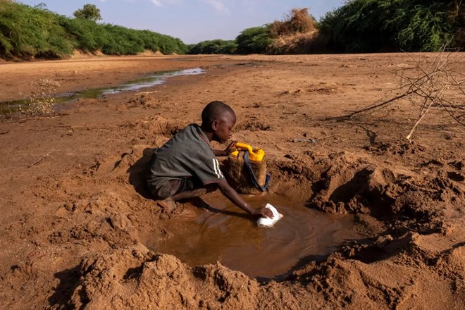 A young boy collects what little water he can from a dried-up river in Dollow Somalia. [Rich/UNICEF]