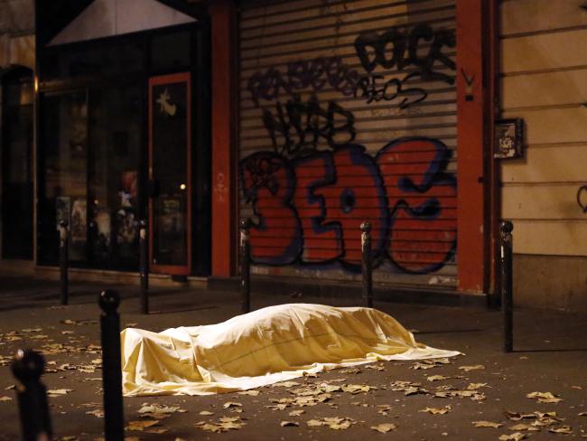 A victim under a blanket lays dead outside the Bataclan theatre.. (AP Photo/Jerome Delay)Source:AP
