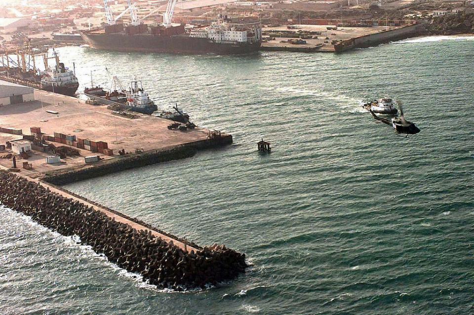 Aerial view of the Port of Mogadishu. Three cargo ships, large, medium and small sized vessels are moored to the docks. A tugboat is heading out of the port. PHOTO - U.S. GOVERNMENT