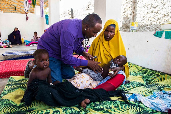 Hussein Kassim Ali, director of Kismayo hospital in South Somalia, examines Maryan, 8 months, lying on her mother’s lap, and her brother Maseuud. Both children are suffering from measles and Maryan also has pneumonia, a severe complication caused by measles.