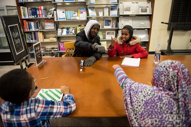 Abdikadir bumped fists with one of his students at the East Lake Library Thursday night. He spends a few hours most weeknights tutoring young Somali kids in mathematics.