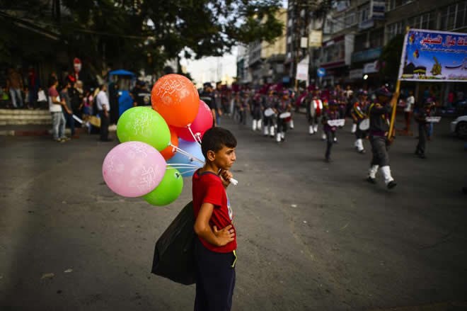 GAZA CITY, GAZA – SEPTEMBER 11: A boy with balloons watches the scout band members march to Unknown Soldier’s Square as they gather for Muslim sacrificial festival “Eid al-Adha” in Gaza City, Gaza on September on 11, 2016. ( Mustafa Hassona – Anadolu Agency )