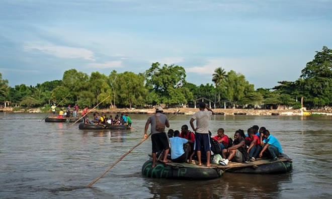 African and Haitian migrants cross the Suchiate river at the border between Guatemala and Mexico. Local rafters charge them eight times the normal rate. Photograph: Encarni Pindado for the Guardian