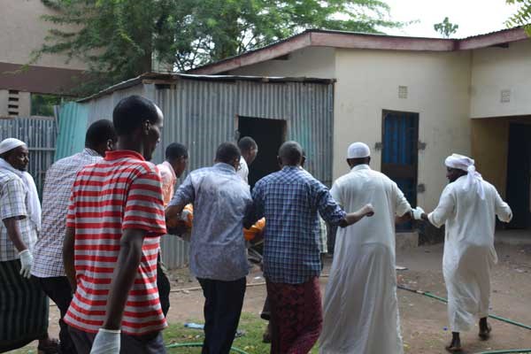 Residents assist police officers to carry away the body of one of the three people found murdered in Garissa Town on February 23, 2017. PHOTO | ABDIMALIK HAJIR | NATION MEDIA GROUP