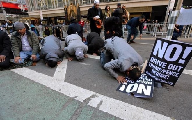 Muslim men kneel on Broadway Ave. as they take part in afternoon prayers CREDIT: CARLO ALLEGRI/X90181