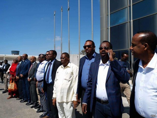 Somali officials line up at Mogadishu's airport to welcome Somali migrants from Libya, Feb. 17, 2018. (H.K. Qoyste/VOA)