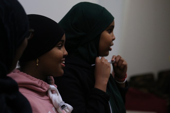 Suweyda (middle) and Salma (right) watch as others continue to dance. Esther taught her children to cook Somali food, showed them Somali culture on TV and danced with them at home as well. Esther said she knows it’s different because her children have never been to Somalia. (Photo by Ester Ouli Kim.)